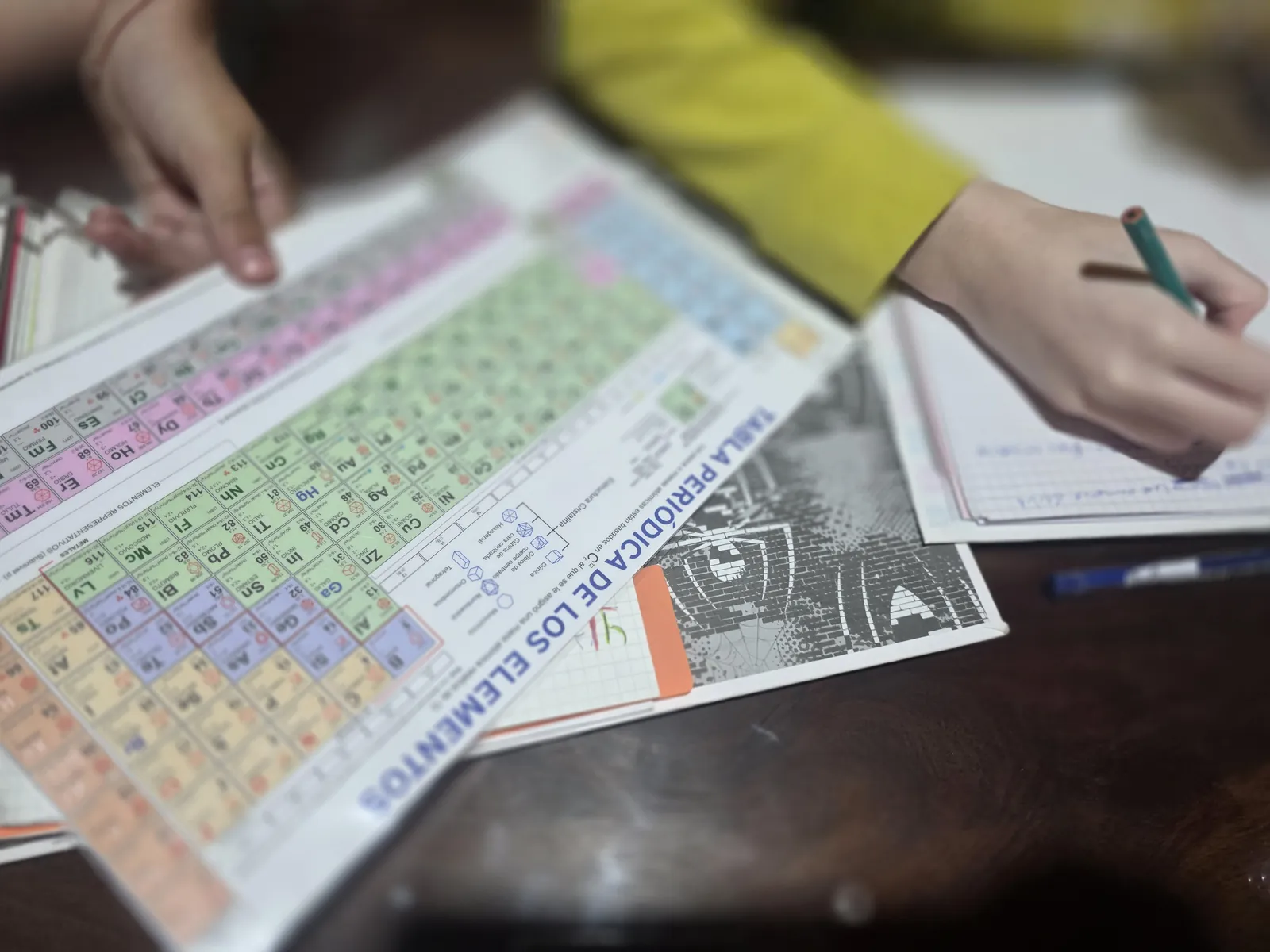 Una estudiante trabaja con la tabla periódica y su carpeta durante un encuentro de acompañamiento.