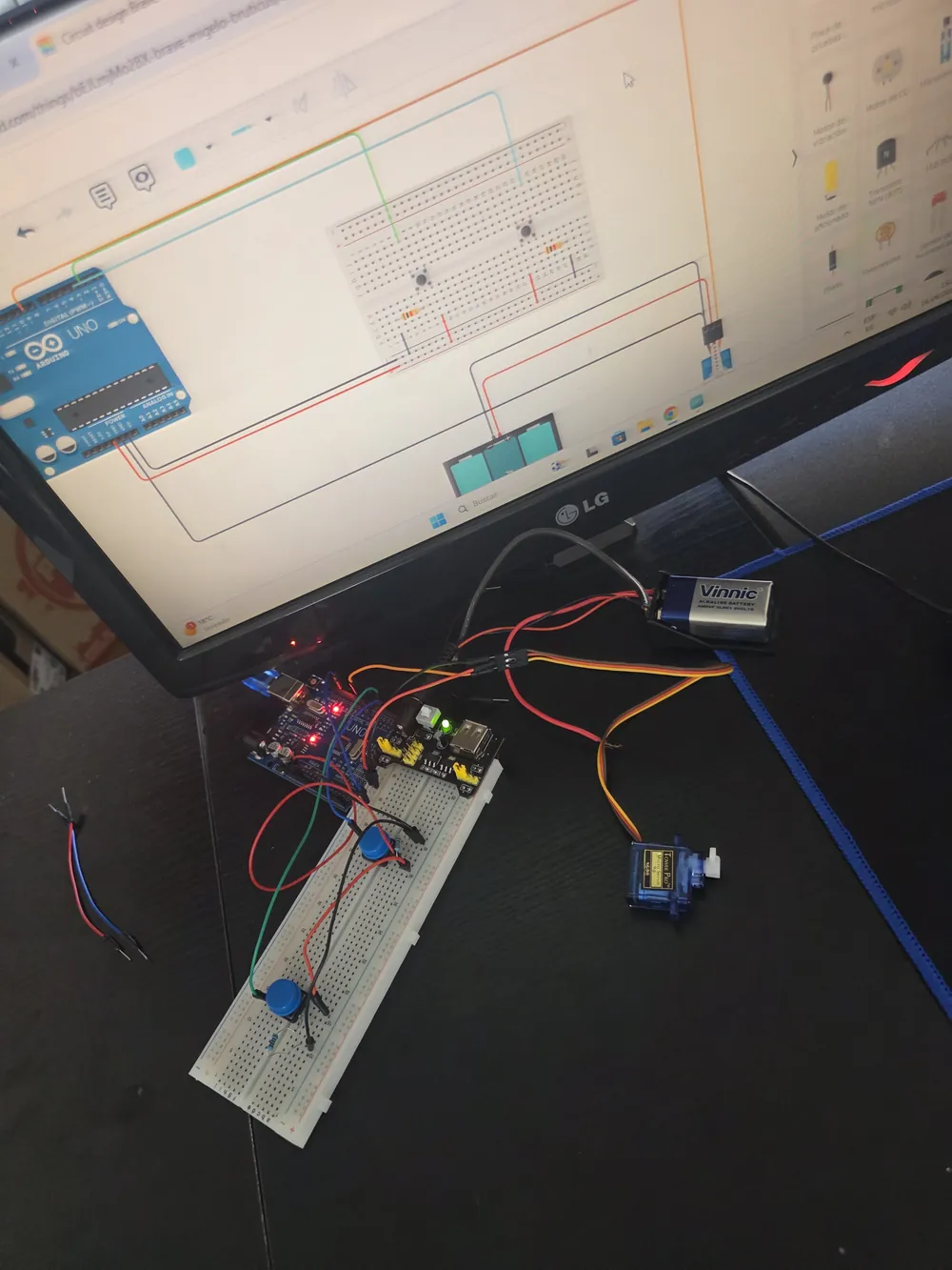 El mismo circuito dos veces: simulado en la pantalla y armado en protoboard con placa Arduino, servomotor y batería.